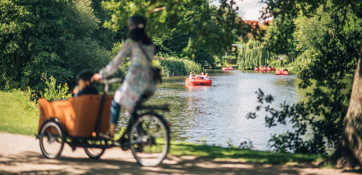 Kvinde på christianiacykel med vandcykler på aaen i baggrunden
