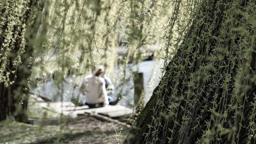 Couple sitting by the river behind tree