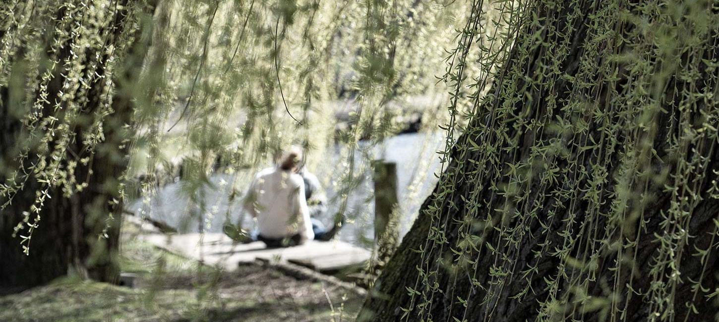 Couple sitting by the river behind tree