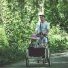 Mand cykler i grønne omgivelser med børn i ladcykel